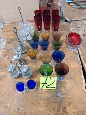 de nombreux objets en verre de différentes couleurs posés sur une table en bois
