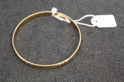 a close up of a gold bracelet with a tag on it