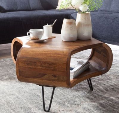a coffee table with a magazine on it and a vase of flowers on top of it