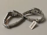 two silver bracelets with tags on them on a table