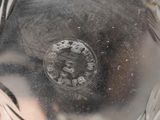 a close up of a silver vase with a face on it