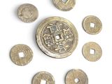 Plusieurs vieilles pièces chinoises sont disposées en cercle sur une surface blanche.