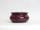 a small red vase sitting on a white surface