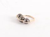 une photo en gros plan de deux perles noires sur une bague en or