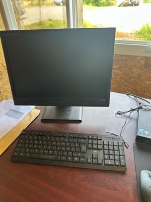 un écran d'ordinateur et un clavier posés sur un bureau devant une fenêtre