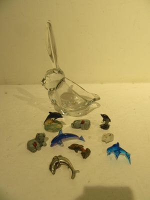 un oiseau en verre posé sur une table, à côté d'autres animaux en verre