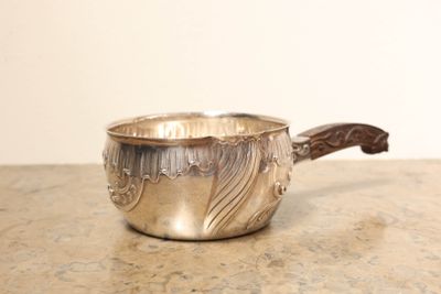 une saucière en argent avec une poignée, posée sur une table