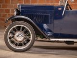 a blue vintage car parked in front of a brick wall