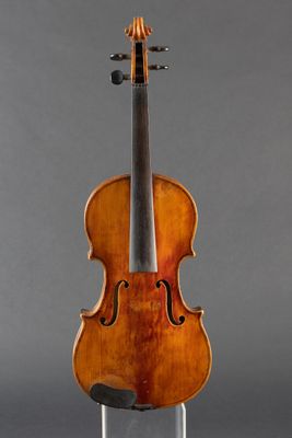 an old violin sitting on a stand against a gray background