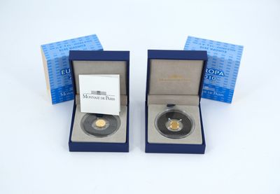 deux pièces d'or dans une boîte bleue posée sur une surface blanche