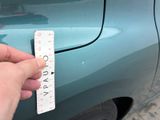 a person holding a ruler that is on the side of a car