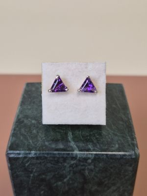 une paire de boucles d'oreilles violettes posées sur un bloc de marbre