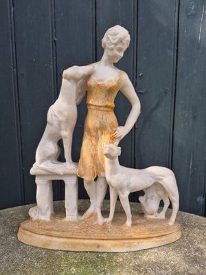 statue of a woman and two dogs on a bench in front of a black wall