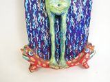 a sculpture of a frog that is sitting on a piece of cloth