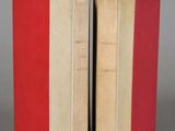 two red and white books sitting next to each other on a gray surface