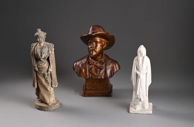 trois statues d'hommes coiffés de chapeaux et vêtus de capes, posées sur une surface grise