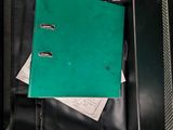 a green binder sitting inside of a black suitcase