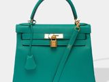 a green leather handbag with a gold lock on the handle