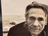 an old photo of a man standing on a beach with the ocean in the background