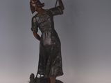 bronze statue of a woman holding a golf club on a wooden base