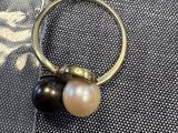 un gros plan d'une bague ornée de deux perles