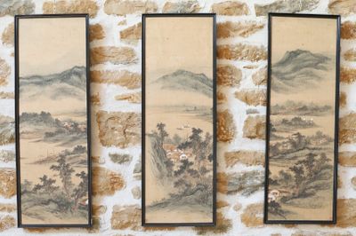trois peintures asiatiques accrochées à un mur, à côté d'un mur de briques