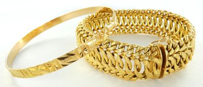 deux bracelets en or posés sur une surface blanche, sur fond blanc