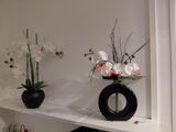 two vases with flowers on a shelf in a room