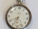 une montre de poche en argent posée sur une surface blanche