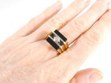 a woman ' s hand holding a black and gold ring