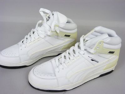 une paire de baskets blanches à semelles noires posées sur une surface grise