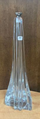 un vase en verre transparent posé sur une table, avec un mur marron en arrière-plan