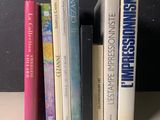 Plusieurs livres sont alignés sur une étagère devant un mur noir
