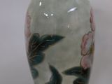 a vase with flowers painted on it sitting on a table