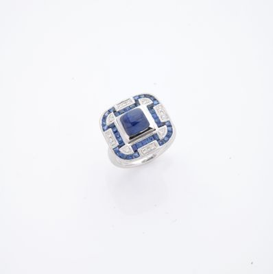 un gros plan d'une bague posée sur une surface blanche, sertie d'une pierre bleue