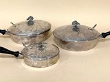 trois casseroles et poêles posées sur une table