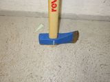 a hammer stuck in the floor with a toothbrush