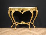a gold console table with a marble top on a wooden floor