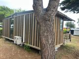 a tiny house that is sitting next to a tree