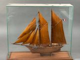 maquette en bois d'un voilier, présentée dans une vitrine posée sur un socle en bois