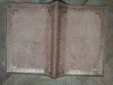un livre rose aux bords dorés posé sur un parquet