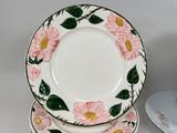 three plates with pink flowers on them sitting on a table
