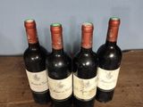 four bottles of wine are lined up on a wooden table