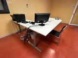 a desk with two computers and a chair in the room