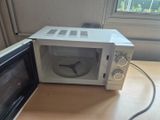 un micro-ondes blanc posé sur une table près d'une fenêtre