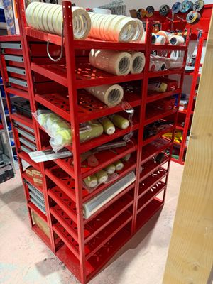 many rolls of thread on a red rack in a store