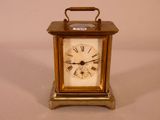 une petite horloge en laiton avec des chiffres romains sur le cadran