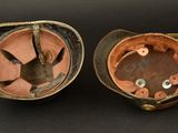 pair of antique leather hats with metal buttons and a leather strap