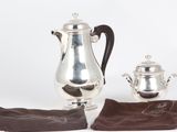 a silver coffee pot and a silver tea pot on a white plate