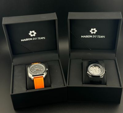 deux montres dans des boîtes noires, munies de bracelets orange